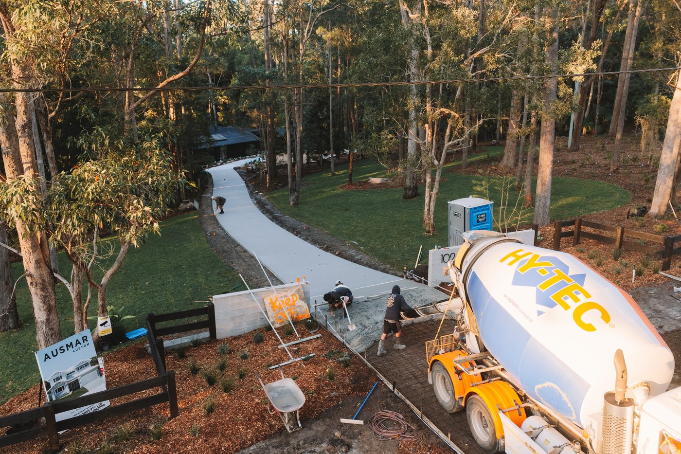 Aerial view of a long concrete driveway curving through bushland with the truck on site