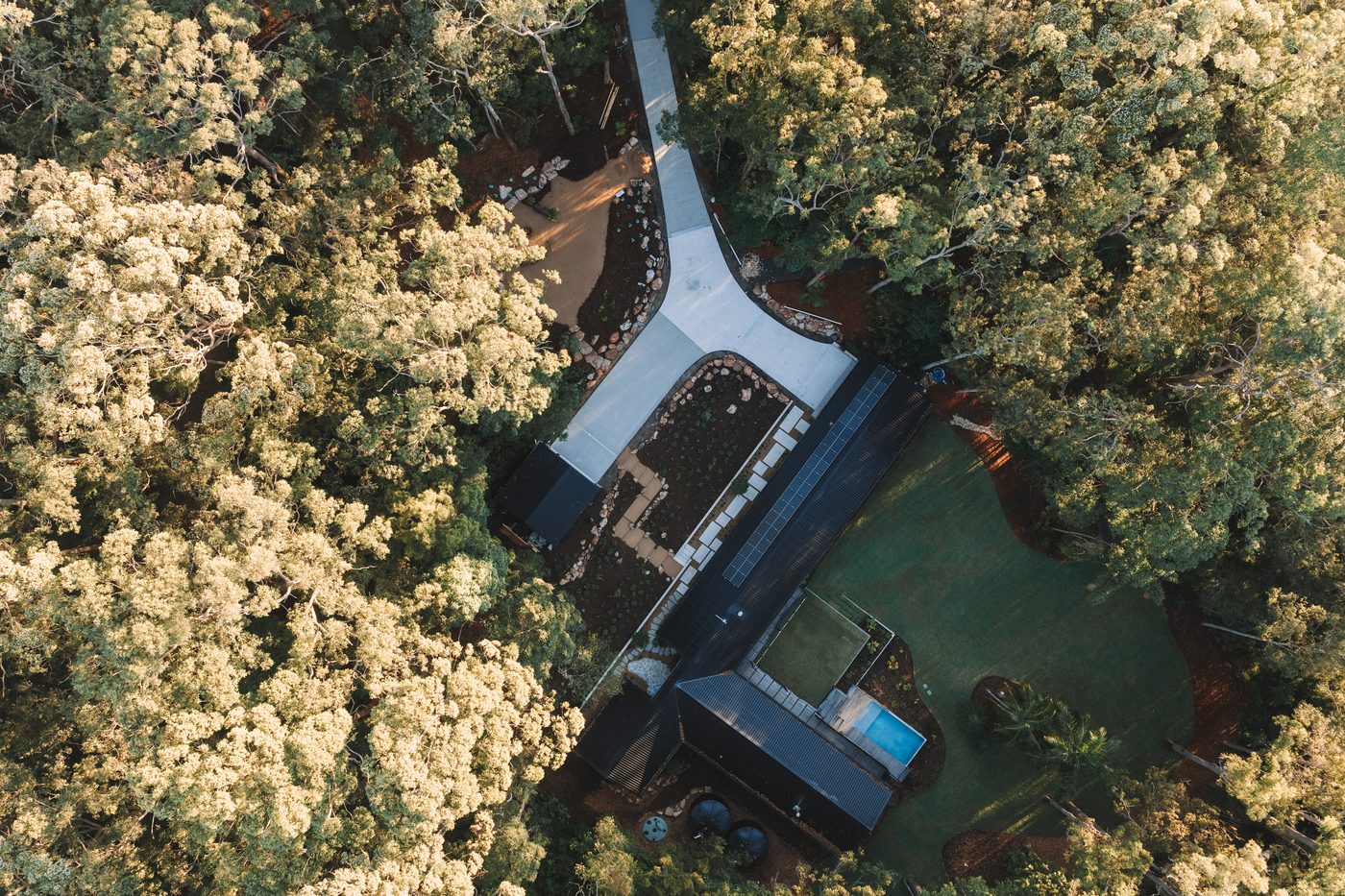 Top-down aerial of a completed concrete driveway and custom home set in Sunshine Coast bushland