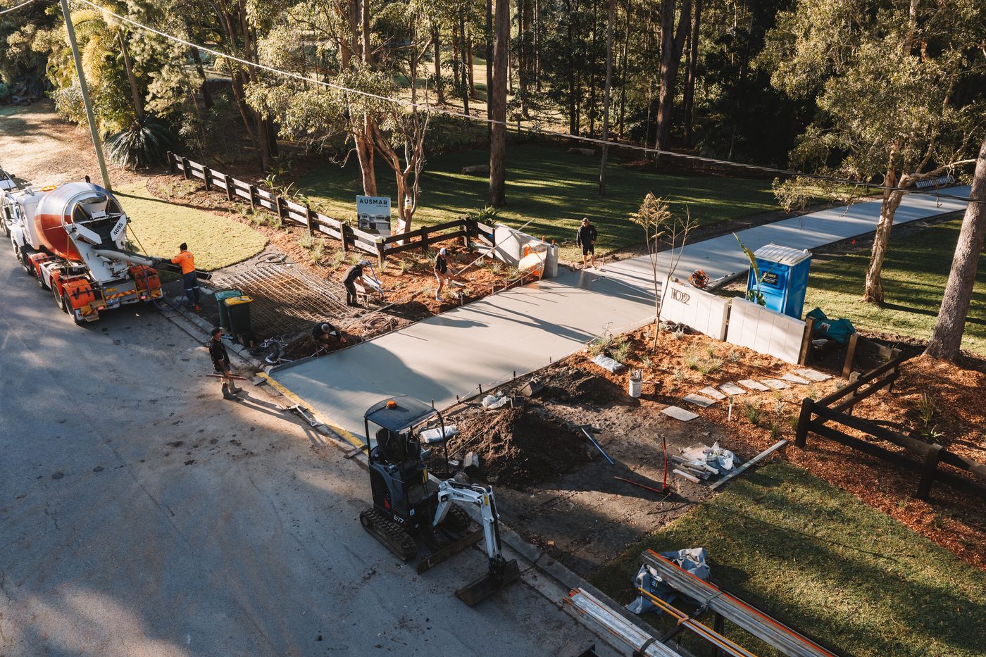 Aerial view of a driveway pour underway with the excavator and crew on site