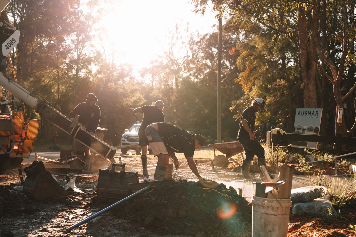 Crew placing concrete across a residential slab at sunrise