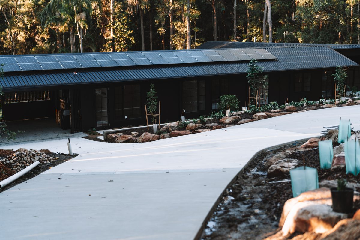 Finished driveway running up to a dark-clad custom home